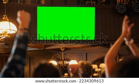 Group of Multicultural Friends Watching a Live Sports Match on TV with Green Screen Display in a Bar. Happy Fans Cheering and Shouting, Celebrating When Team Scores a Goal and Wins the Tournament. Royalty-Free Stock Photo #2234309613