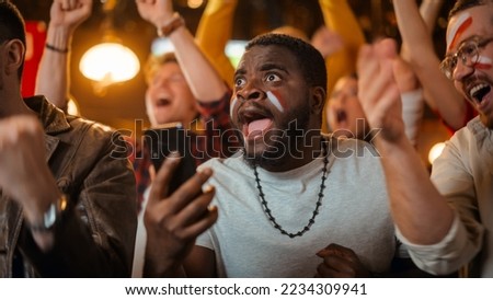 Portrait of an Excited Young Black Man Holding a Smartphone, Anxious About a Sports Bet on His Favorite Soccer Team. Lively Successful Emotions When Football Team Scores a Winning Goal. Royalty-Free Stock Photo #2234309941