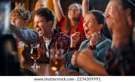 Portrait of a Beautiful Female Sitting at a Pub Counter with Group of Diverse Friends, Watching and Cheering for a Live Soccer Match. Supportive Fans Cheering, Applauding, Shouting and Drinking Beer. Royalty-Free Stock Photo #2234309991