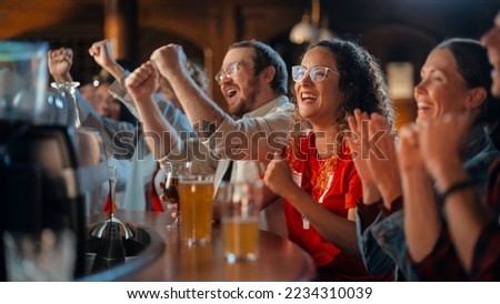 Group of Soccer Fans Sitting at a Bar Counter, Drinking, Watching a Live Football Match Broadcast on TV. People Cheering, Supporting Their Team. Crowd Goes Ecstatic When Team Scores a Decisive Goal. Royalty-Free Stock Photo #2234310039
