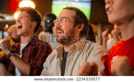 Group of Friends Watching a Live Soccer Match on TV in a Sports Bar. Happy Fans Cheering and Shouting. Young People Celebrating When Team Scores a Goal and Wins the Football World Cup. Slow Motion. Royalty-Free Stock Photo #2234310077