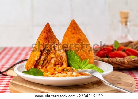 Sicilian rice balls. Conical shaped arancini, stuffed, coated with breadcrumbs and deep fried.  Filled with ragu, minced meat and tomato sauce,  caciocavallo cheese and green peas. Italian food. Royalty-Free Stock Photo #2234319139
