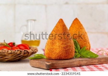 Italian rice balls stuffed, coated with breadcrumbs and deep fried.  Conical-shaped arancini.  Filled with ragu, minced meat, caciocavallo cheese and green peas. Sicilian Royalty-Free Stock Photo #2234319141