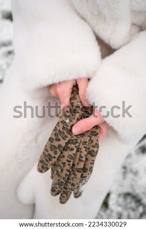 A young woman puts on stylish gloves in leopard print. close-up