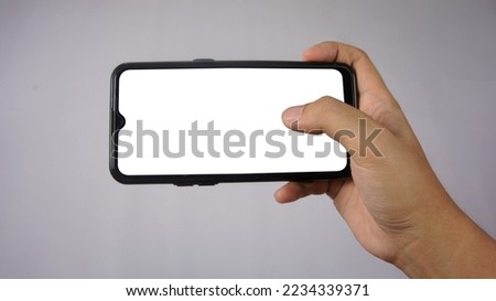A photo of a hand holding a smartphone with a clean white background can be used for mockups of applications, products, games, ui ux design or others
