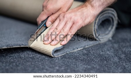 Handyman cutting a new carpet with a carpet cutter..	 Royalty-Free Stock Photo #2234340491