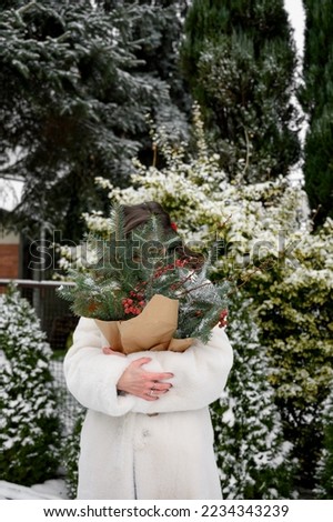 woman holding winter outfit outdoors with christmas tree bouquet. Christmas mood in winter day