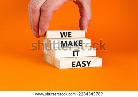 We make it easy symbol. Concept words We make it easy on wooden cubes. Beautiful orange table orange background. Businessman hand. Business motivational we make it easy concept. Copy space.