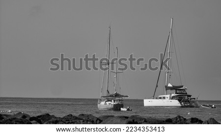 photos of ships near the port of Tenerife (Canary Islands). Modern and new sailboats anchored near a beach with a calm sea in a sunny day.