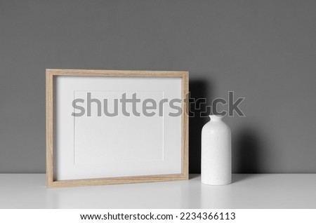 Landscape wooden frame mockup with vase decor over grey wall interior, blank mockup with copy space