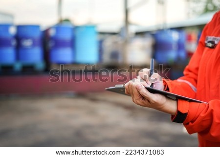 A safety officer is writing on the checklist document during safety audit workplace at the factory. Industrial expertise occupation working scene. Selective focus at hand's part Royalty-Free Stock Photo #2234371083