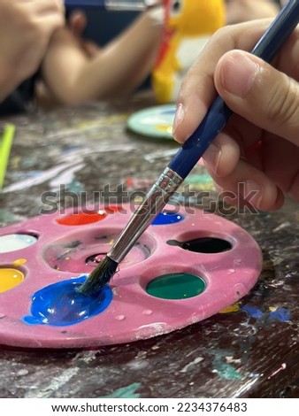 hand of girl put paintbrush in color palette , kid funny painting art