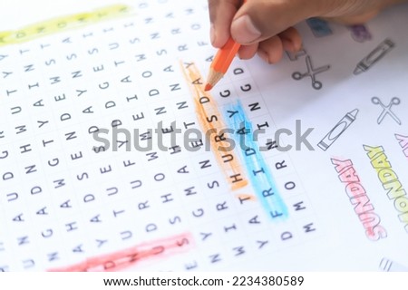 Kid hand doing word search activity in classroom of learning idea in school. selective focus on letter. 