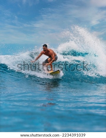 Male surfer on a blue wave at Bali island Royalty-Free Stock Photo #2234391039