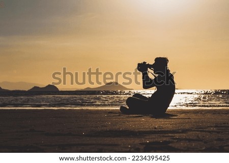 Silhouette of a man taking photos on a sunset beach Labuan Bajo, Indonesia