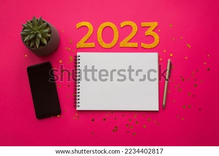 New Year empty goals, plans 2023 concept with notebook, phone, flower and pen. flat lay style. Christmas planning concept with empty space. Viva magenta background. Color of the year