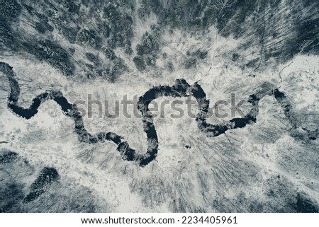 Aerial view of the winding river against the backdrop of snowy fields and winter forest. Meander from the top Royalty-Free Stock Photo #2234405961