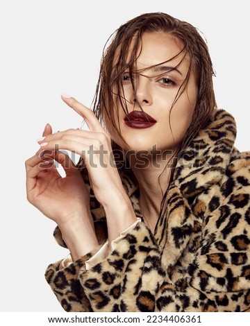 Portrait of young beautiful girl posing in stylish animal print coat isolated over white background. Wet hairstyle. Concept of beauty, skin care, cosmetology, plastic surgery, makeup, fashion