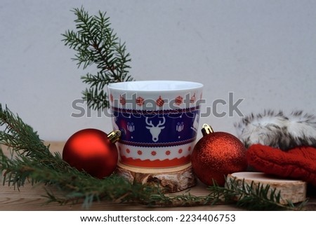 A cup of hot chocolate with two glitter balls, a natural fir branch with pieces of wood and a sock