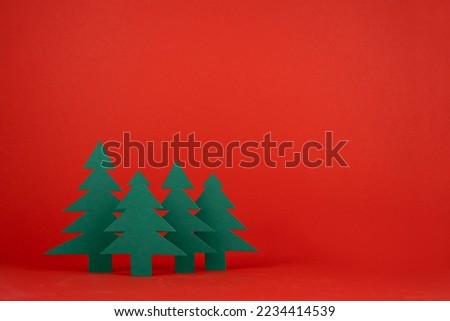 Christmas festive background in traditional red and green color with green paper spruces in minimal cartoon style, copy space. New year mockup for presentation, design, card, poster, flyer.