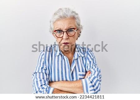 Senior woman with grey hair standing over white background skeptic and nervous, disapproving expression on face with crossed arms. negative person.  Royalty-Free Stock Photo #2234421811