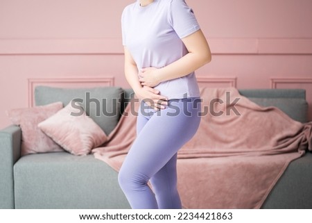 Menstrual pain, woman with stomachache suffering from pms at home, endometriosis, cystitis and other diseases of the urinary system, pink background Royalty-Free Stock Photo #2234421863