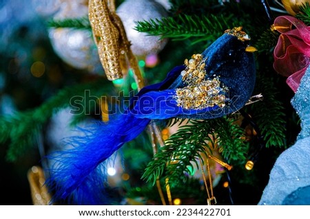 Blue bird with sparkles on a branch of a Christmas tree and a blurred dark background with colorful bokeh. Subject is out of focus. The artistic intend and the filters. Airy atmosphere