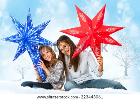 Portrait of Cute girls holding paper stars against winter background.