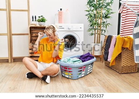 Young blonde girl doing laundry listening to music at home.