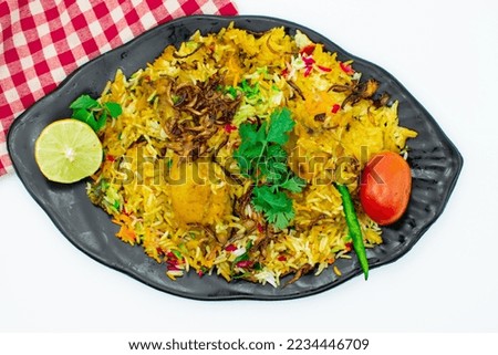 Isolated delicious spicy chicken biryani in black plate on white background