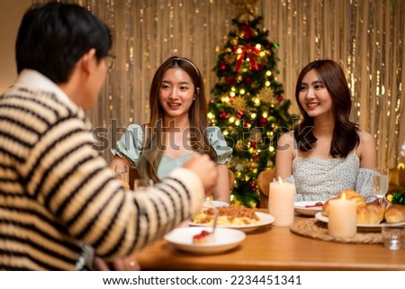Young people talking and eating dinner while celebration and toasting with champagne together in holiday of new year party at home.