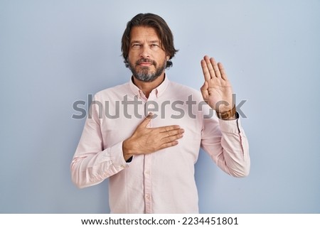 Handsome middle age man wearing elegant shirt background swearing with hand on chest and open palm, making a loyalty promise oath  Royalty-Free Stock Photo #2234451801