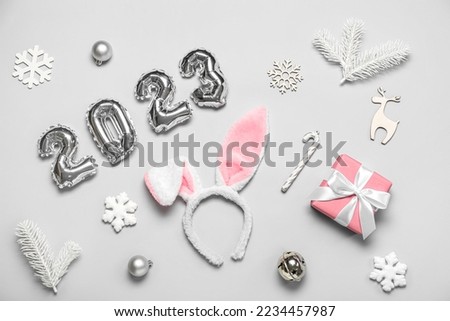 Figure 2023 made of balloons with bunny ears and Christmas decor on grey background
