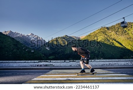 Bearded man Skater ride in the mountain road on his longboard in Medeo Dum Almaty, Kazakhstan