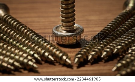 photo of a group of bronze-colored screws in close - up , photographed on a wooden table lying down