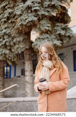 beautiful young woman with takeaway coffee outdoors in cold weather