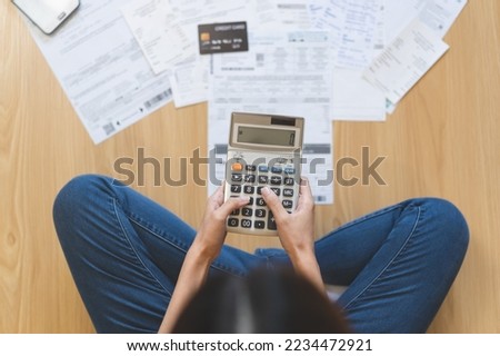 Stress asian young employee woman hand use press on calculator to calculate budget, cost income, expenses of credit card on statement for payment, sitting on floor at home. Financial, finance people. Royalty-Free Stock Photo #2234472921