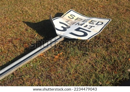 Bent and Toppled Speed Limit Street Sign Lying on Grass.