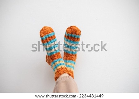 Legs in woolen socks on a white background. Warm socks for winter cold. Handmade knitting. Royalty-Free Stock Photo #2234481449