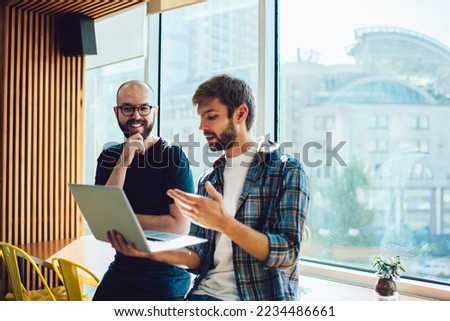 Low angle of male freelancers making investment in successful startup on portable computer and checking earnings while coworking in modern workspace Royalty-Free Stock Photo #2234486661