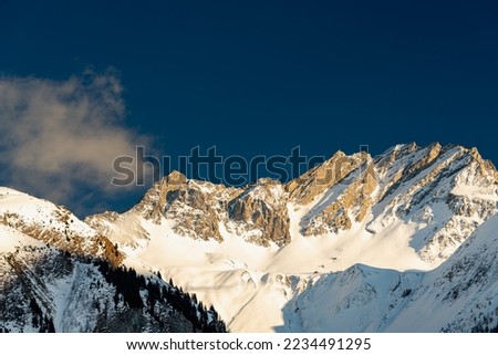 Art prints of a rocky mountain ridge taken in the light of the last warm sun rays at sunset. This wonderful winter panorama in the swiss alps radiates a calming energy and tranquility. Royalty-Free Stock Photo #2234491295