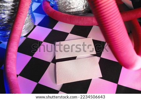 High resolution visit card realistic mockup with trendy groovy style and chess texture background and also pink and blue neon lights. Colorful vibrant photos can be use for Christmas presentation