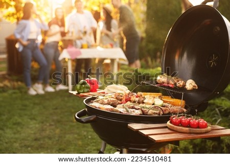 Group of friends having party outdoors. Focus on barbecue grill with food. Space for text Royalty-Free Stock Photo #2234510481