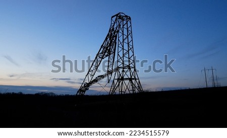 A high-voltage power tower broken as a result of a missile strike against the sky. Russia is carrying out missile strikes on the energy system of Ukraine. Blackout Royalty-Free Stock Photo #2234515579