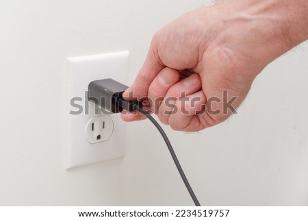 Person connecting usb adapter plug into electrical wall outlet Royalty-Free Stock Photo #2234519757