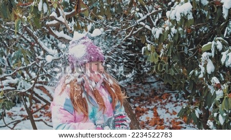 Happy Beautiful Caucasian Girl Playing Snow Battle with Friends in Park Gets Hit in Head by Snowball