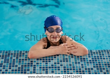 The girl is playing and learning to swim in a modern swimming pool. Development of children's sports. Healthy parenting and promotion of children's sports. Royalty-Free Stock Photo #2234526091