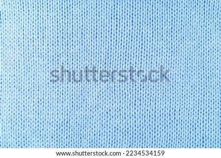 Close up background of knitted wool fabric made of viscose yarn. Pastel blue color wool knitwear texture. Abstract knitted jersey background. Fabric abstract backdrop, wallpaper Royalty-Free Stock Photo #2234534159