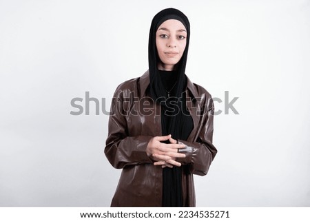 Business Concept - Portrait of beautiful muslim woman wearing hijab and brown leather jacket over white background holding hands with confident face.