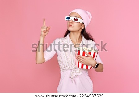 woman in hat with bucket of popcorn pointing at copy space